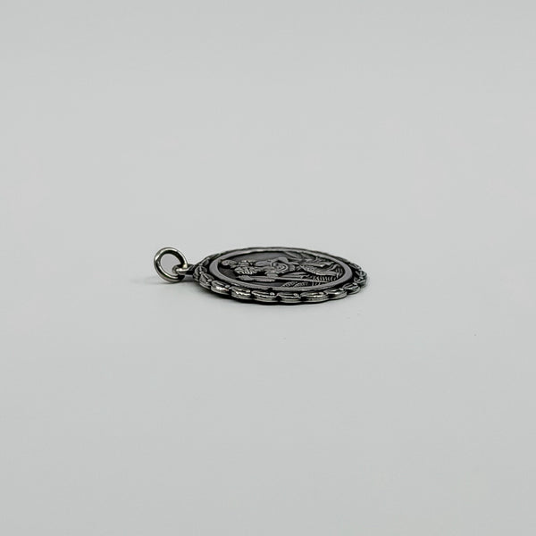 Low side view of vintage sterling silver St Christopher pendant charm showing its slim profile.