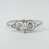 Close-up of sterling silver bangle with spiral design and bezel-set oval mother of pearl