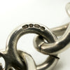 Close up of sterling silver hallmark on vintage charm bracelet link, showing maker and assay marks.