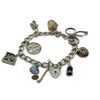 Vintage sterling silver charm bracelet with 8 charms, heart lock and safety chain on white background.