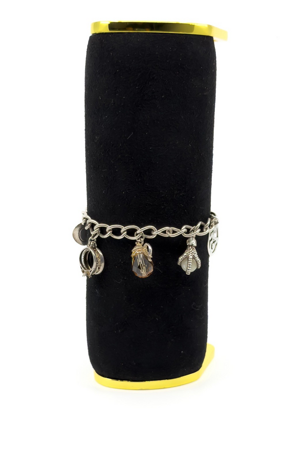 Side display of vintage sterling silver charm bracelet with mixed charms hanging from oval links.