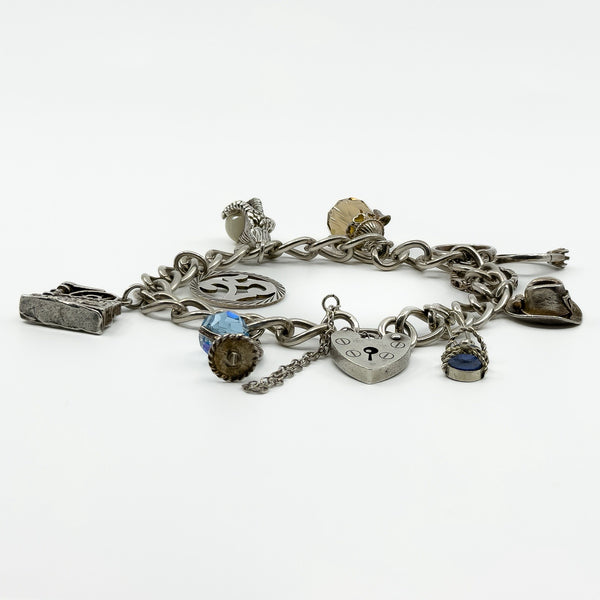 Vintage sterling silver oval link charm bracelet shown from the side with heart lock and hanging charms.