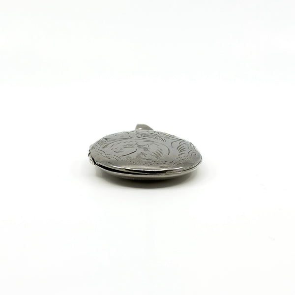Side view of a vintage sterling silver oval photo locket showing engraved detail and rounded depth