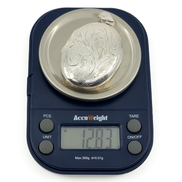 Vintage sterling silver oval engraved photo locket shown weighing 12.83g on digital scales