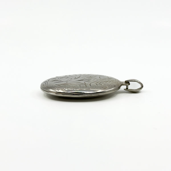 Side profile of a sterling silver oval photo locket showing its chunky depth and bail