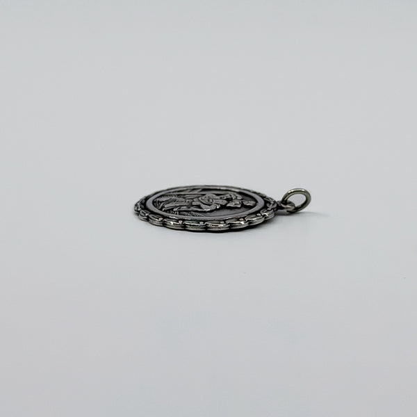 Side view of sterling silver St Christopher pendant charm showing the textured edge and jump ring.