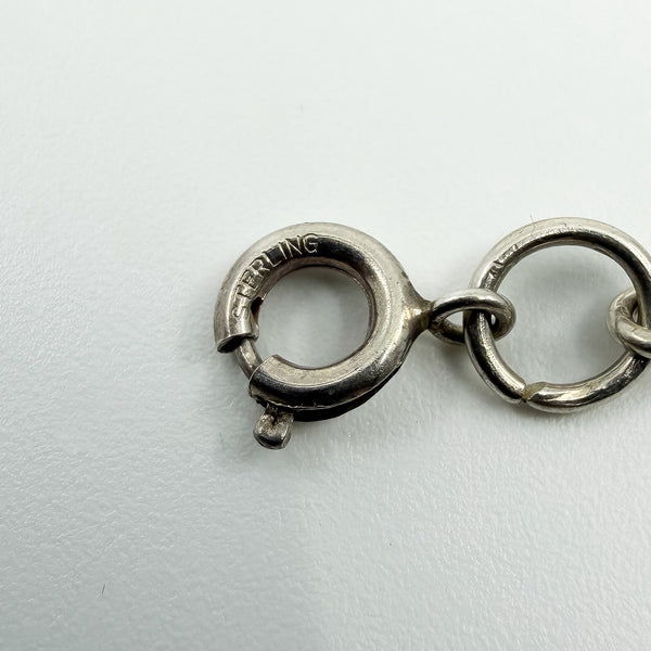 Close up of the spring clasp stamped STERLING on a vintage silver open heart necklace
