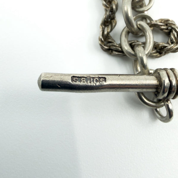 Close-up of the sterling silver T-bar showing stamped maker’s mark and chain links