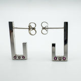 Pair of sterling silver J half hoop earrings with pink sapphires and diamond bezel set at the base