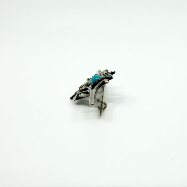 Close side view of the brooch showing the pin, hinge and C hook clasp fitting.
