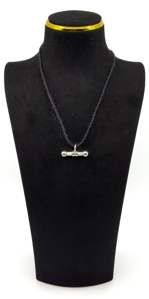 Sterling silver T-bar charm shown hanging on a cord on a black jewellery bust.