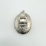 Overhead view of vintage silver buckle locket with floral engraving