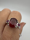 Top-down view of ruby trilogy ring worn on finger, showing gemstone colour contrast