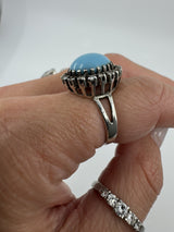 Side view of the turquoise diamond halo ring worn on the hand, showing the high setting