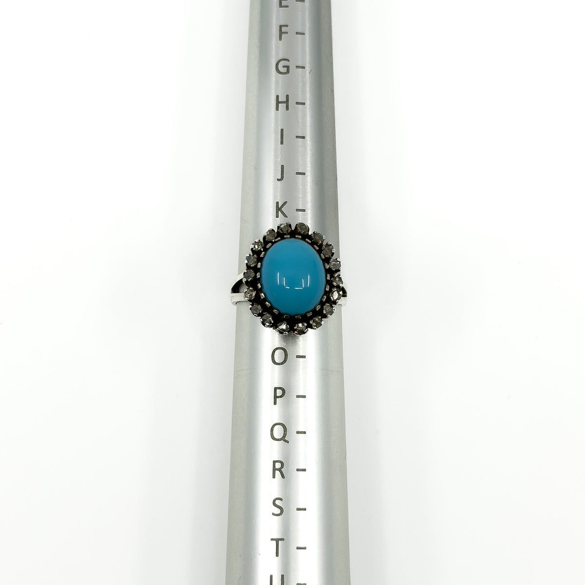 Sterling silver turquoise diamond halo ring shown on a UK ring mandrel at size L - M