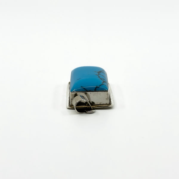 Low side view of sterling silver turquoise pendant showing the raised blue stone and silver frame