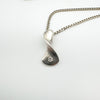 Pendant with sculptural twist design and inset diamond on silver chain