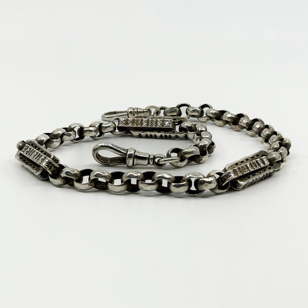 Low angle view of antique sterling silver Albert chain with engraved bars and two dog clips