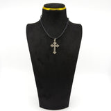 Antique silver cross pendant shown on a black necklace display with engraved detail