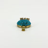 Low side view of the antique turquoise locket showing the domed gemstone setting, gold frame and bail.