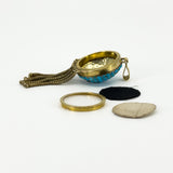 Side view of the open Victorian locket with its removable back components, bail and articulated tassels.