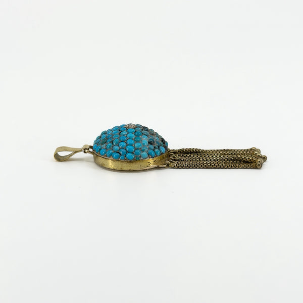 Side profile of antique 18ct gold turquoise locket showing the domed setting, bail and articulated tassels.