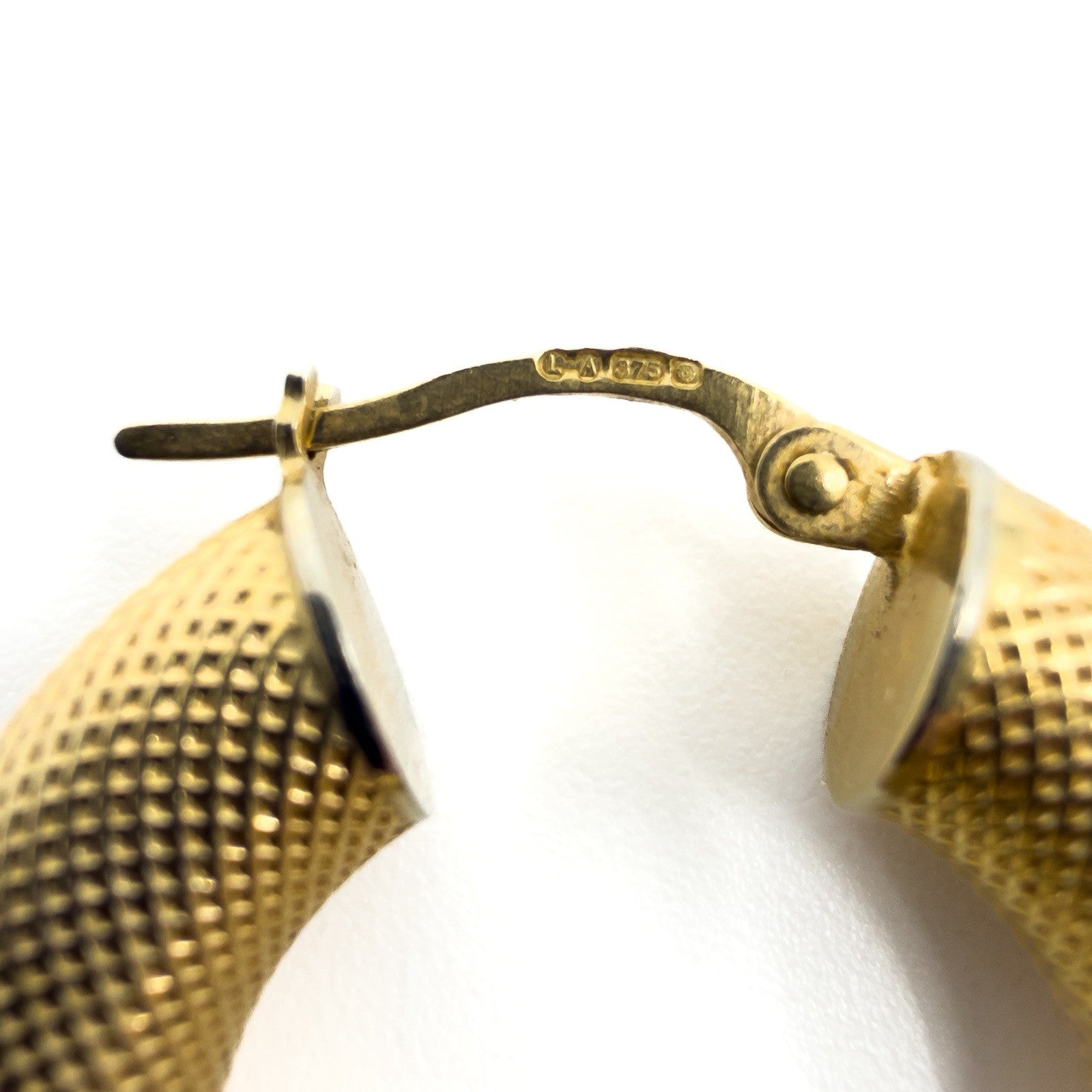 Close up of the 375 and assay marks on the 9ct gold mesh hoop earring fitting.