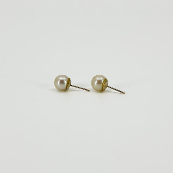 Side view of vintage 9ct gold pearl studs showing the round white cultured pearls, gold cups and post fittings.
