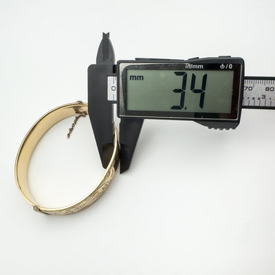 Depth measurement of vintage foliate engraved gold bangle at 3.4mm