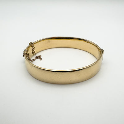 Interior view showing plain back of gold bangle with safety chain