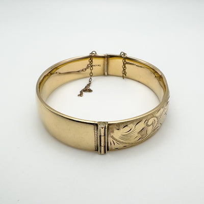 Side view of foliate engraved rolled gold bangle with chain