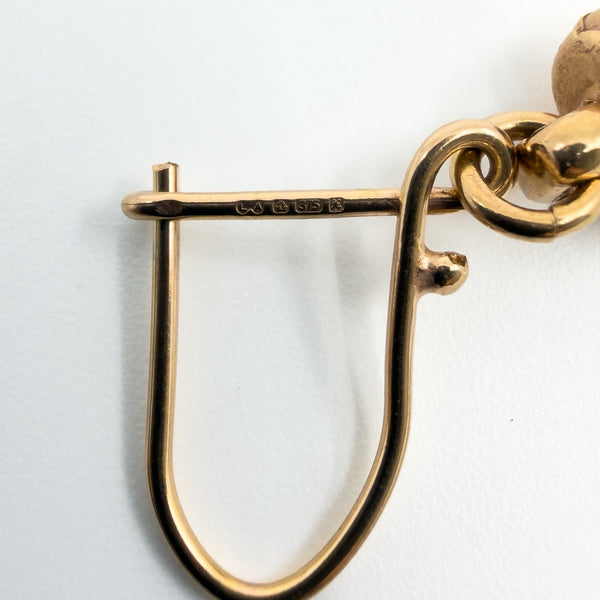 Close-up of the earring wire showing LA, import mark, 375 and date letter x hallmarks.