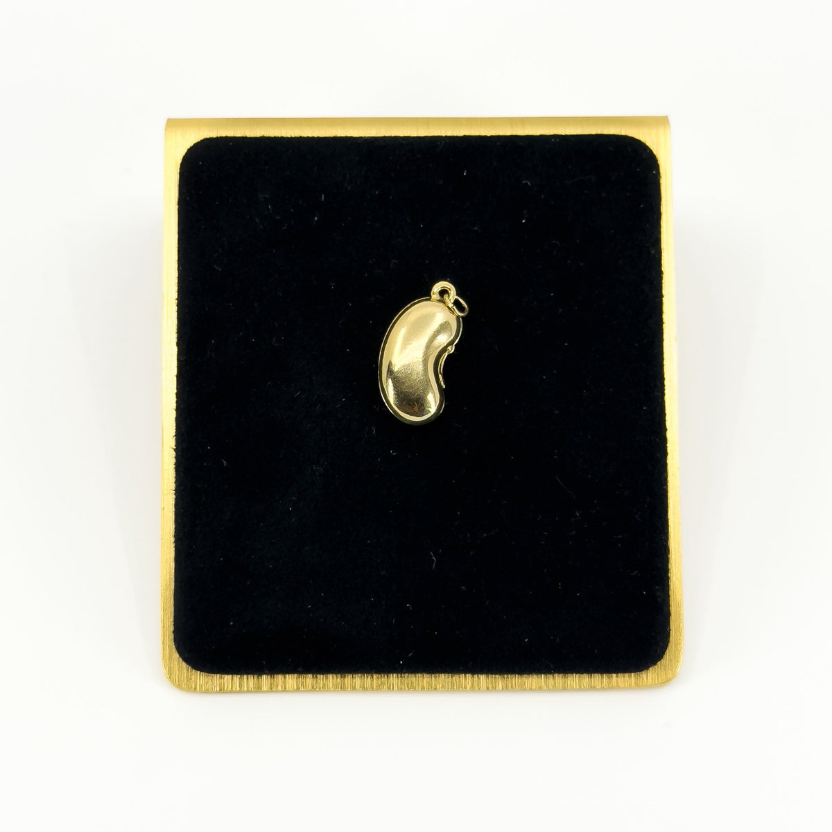 Vintage 9ct gold lucky bean charm pendant displayed on black velvet with polished kidney bean form.