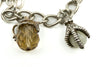 Close up of vintage sterling silver charm bracelet with amber crystal and mother of pearl claw charms.