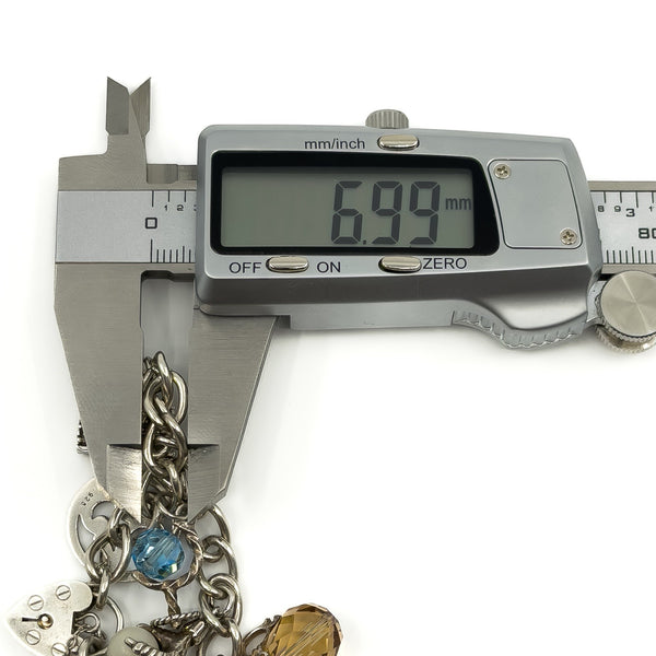 Vintage sterling silver charm bracelet link measurement shown as approximately 6.99mm with charms visible.