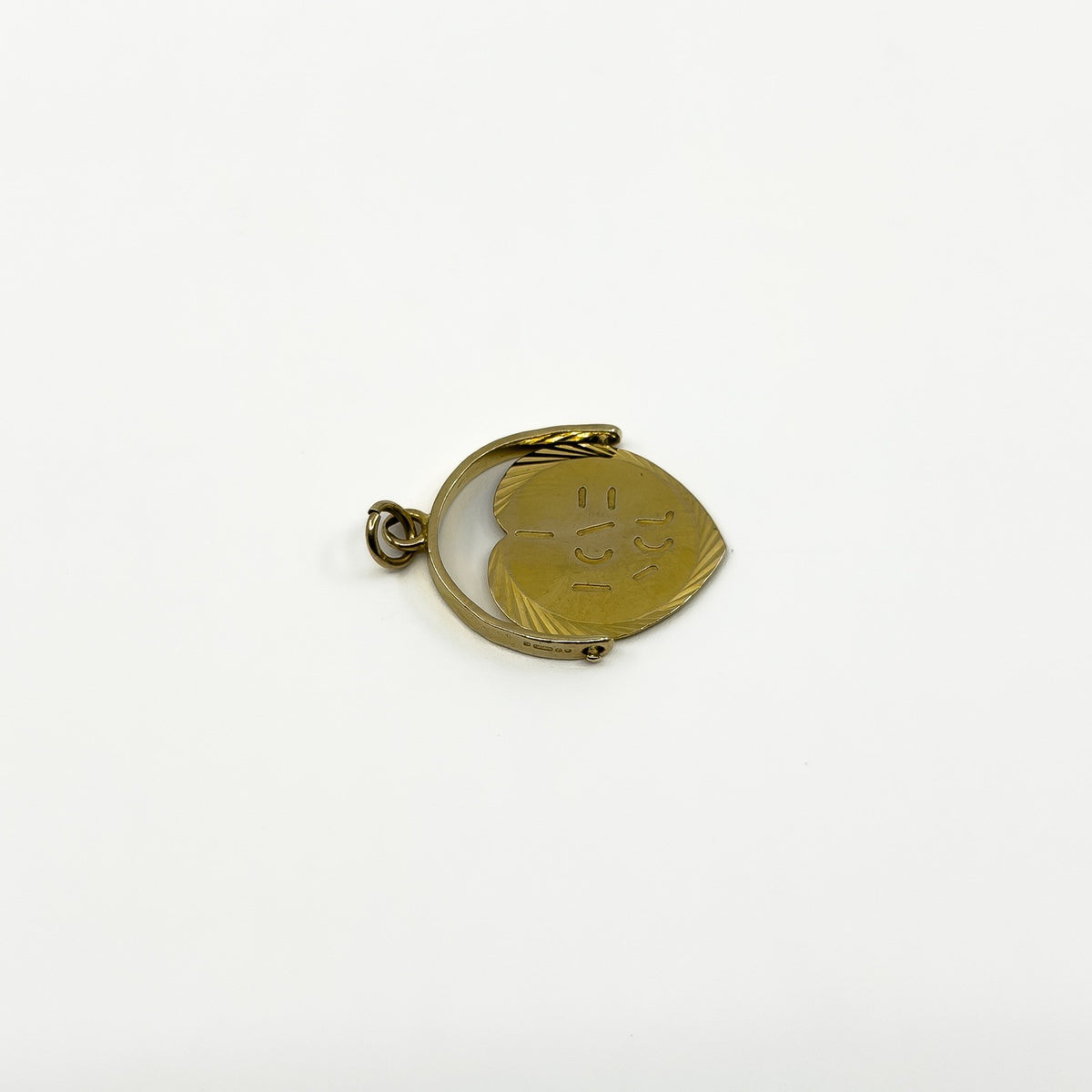 Side view of vintage 9ct gold spinning fob pendant showing round frame, bail and moving disc