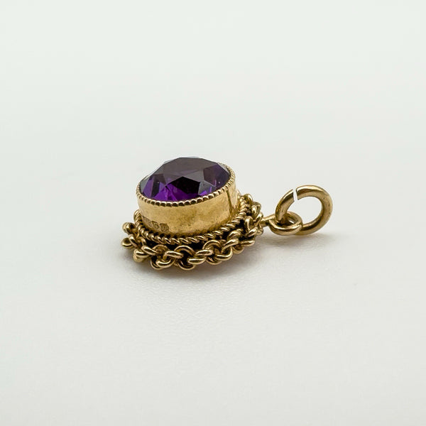 Angled view of amethyst pendant showing gold setting and jump ring