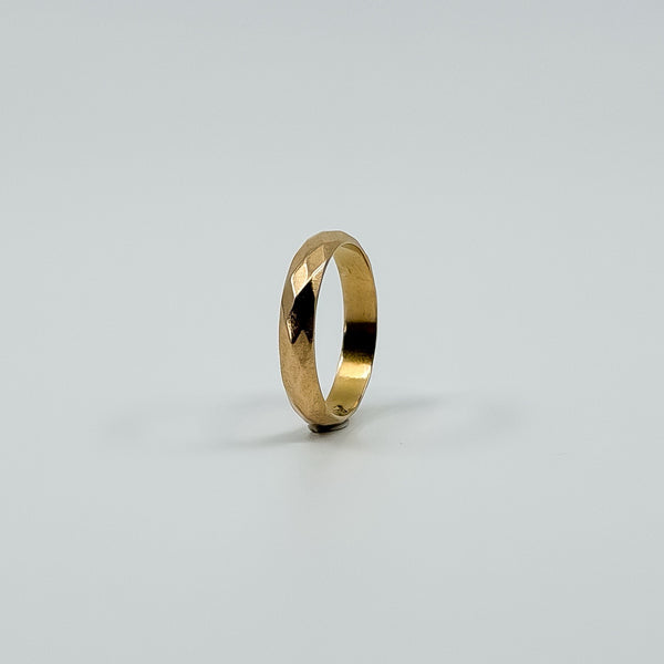 Upright angled view of vintage 18ct rose gold faceted band ring showing the slim full band shape.