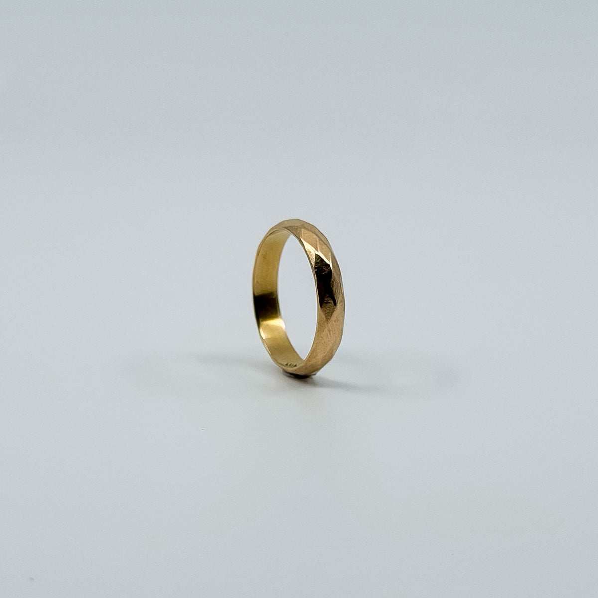 Side view of vintage 18ct rose gold faceted band ring showing the polished faceted surface.