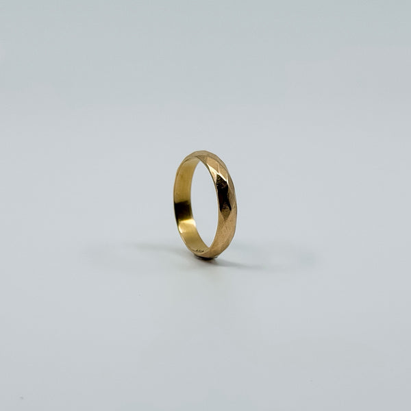 Side view of vintage 18ct rose gold faceted band ring showing the polished faceted surface.