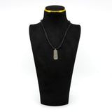 Vintage sterling silver ingot pendant shown on display cord with engraved bird and leaf design.