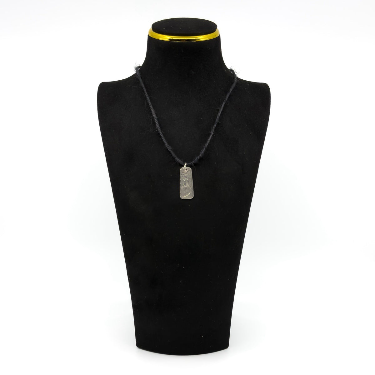 Vintage sterling silver ingot pendant shown on display cord with engraved bird and leaf design.