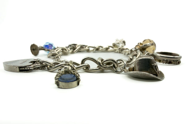 Low angle view of vintage sterling silver charm bracelet with lapis lazuli, cowboy hat and ring charms.