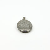 Close side view of a vintage sterling silver locket with foliate engraving