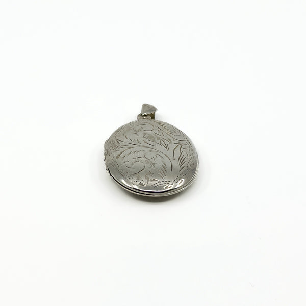 Close side view of a vintage sterling silver locket with foliate engraving