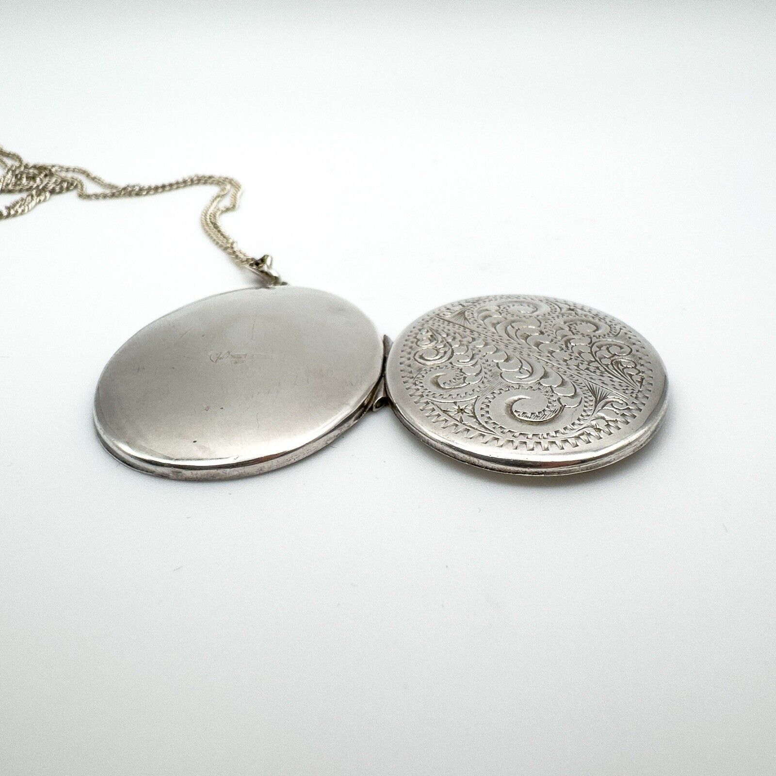 Side view of open sterling silver locket showing outer and inner detail