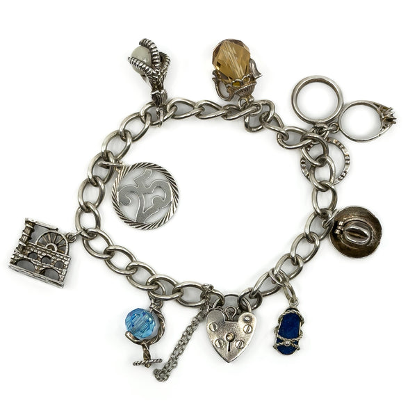 Vintage sterling silver charm bracelet with heart lock, safety chain and assorted charms on oval links.
