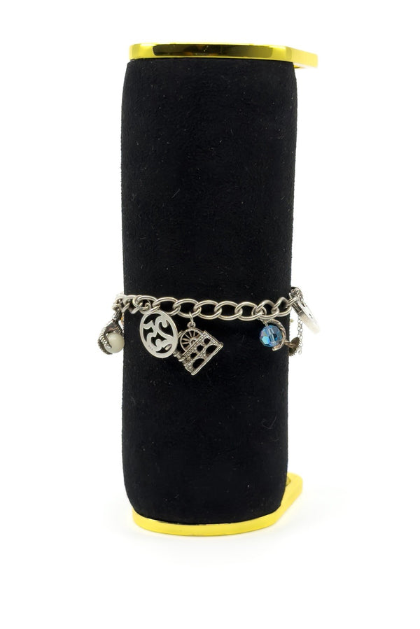 Vintage sterling silver charm bracelet on black display with 925 disc, mill charm and blue crystal globe charm.