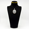 Vintage sterling silver oval locket with floral engraving shown on a black display bust