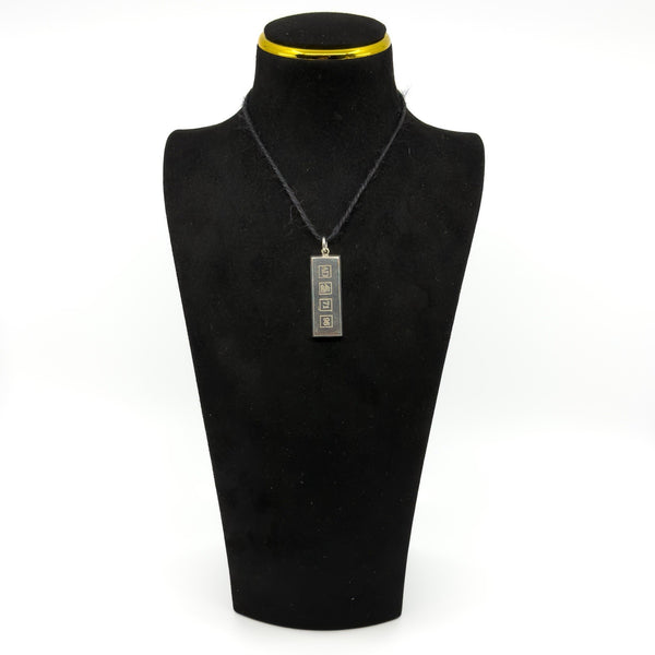 Vintage sterling silver ingot pendant on a black display bust, showing the front hallmark design.